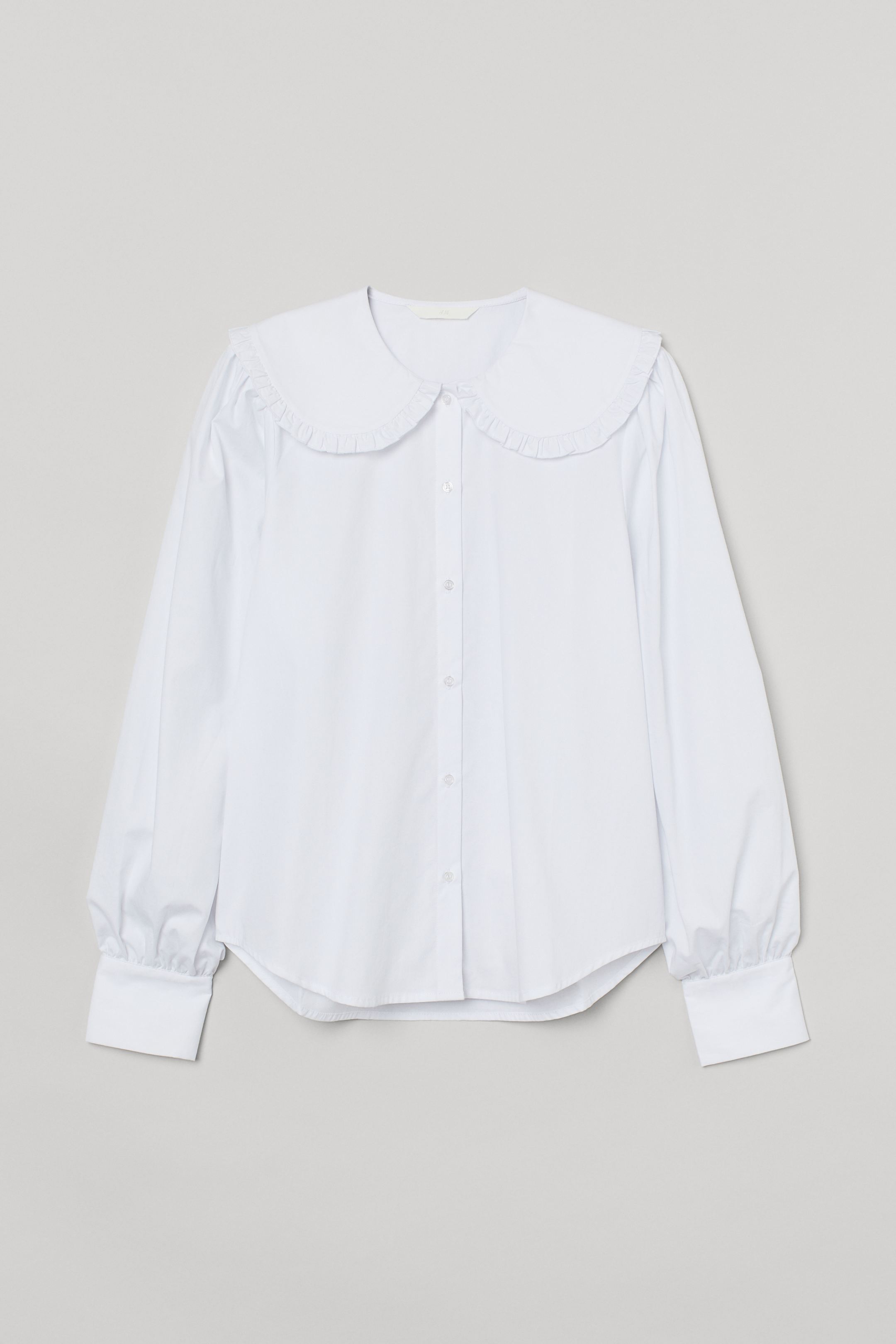 Vaporous cotton blouse with wide double collar with ruffle and button closure. Straight cut model with long sleeves, wide buttoned cuffs and rounded bottom with slightly longer back.